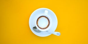 A cup of coffee against a stark yellow background