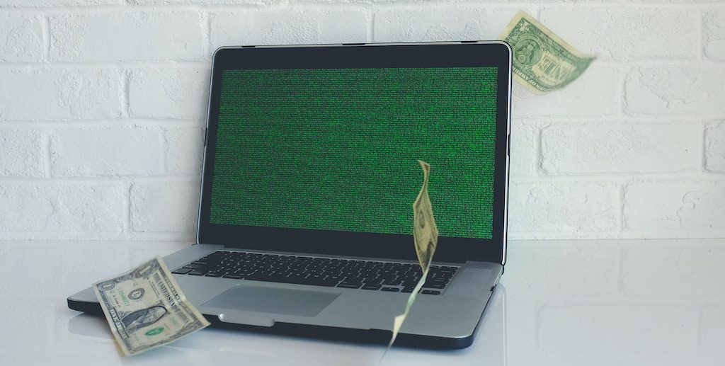 a laptop with money falling around it